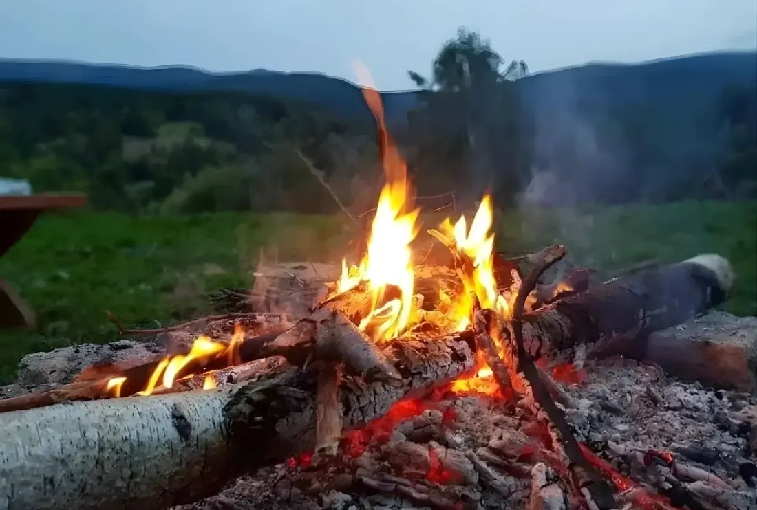 Ognisko w ogrodzie o zmierzchu, w tle góry